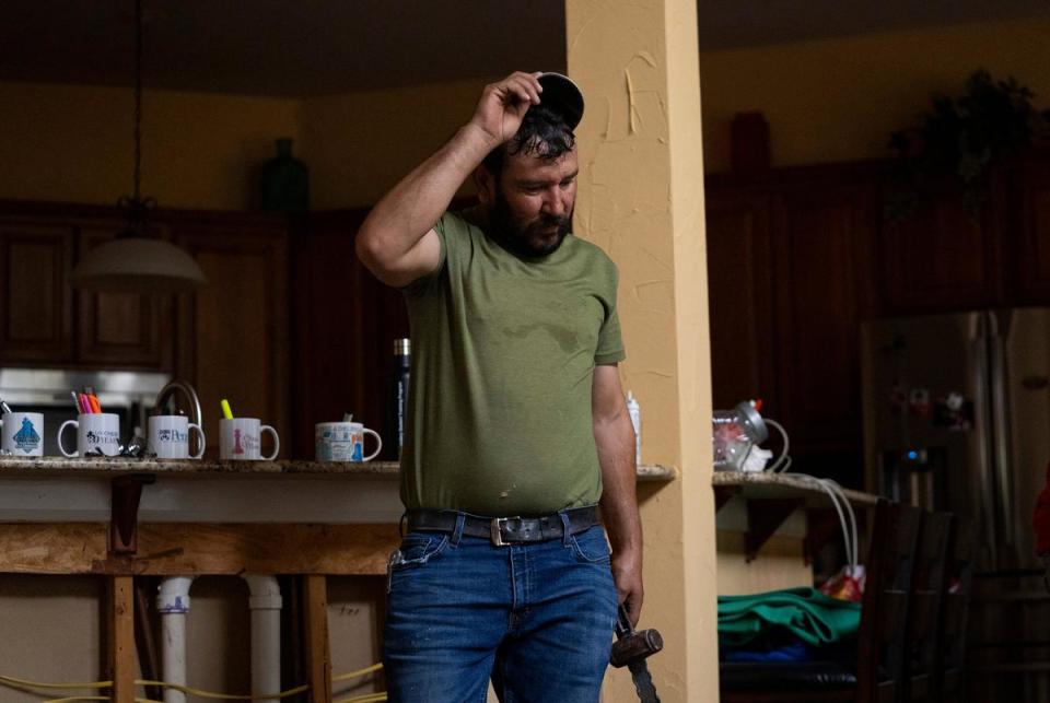 Juan Pedro Muñoz, 45, takes a moment to cool off from the heat and wipe sweat off his head while he works on renovating the floor of a home in Austin on July 7, 2023.