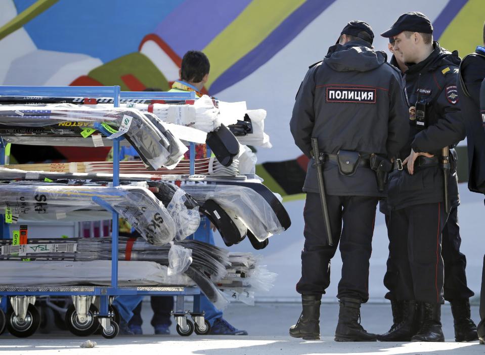 Police officers look over a cart of hockey sticks after they were taken off a plane as NHL hockey players arrive at the Sochi International Airport for the 2014 Winter Olympics, Monday, Feb. 10, 2014, in Sochi, Russia. (AP Photo/Mark Humphrey)