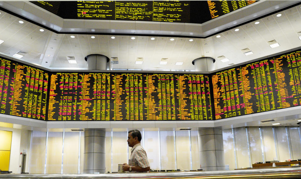 A visitor walks in front of private stock trading boards at a private stock market gallery in Kuala Lumpur, Malaysia, Friday, Dec. 7, 2018. Asian shares were mostly higher Friday after gains on Wall Street but investors continued to watch for news about U.S.-China trade friction. (AP Photo/Yam G-Jun)