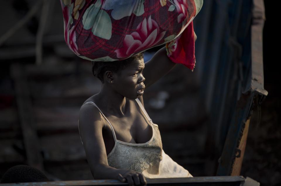 In this photo taken Thursday, Jan. 2, 2014, a displaced woman arrives with what belongings she had time to gather by river barge from Bor, one of the thousands who fled the recent fighting between government and rebel forces in Bor by boat across the White Nile, in the town of Awerial, South Sudan. (AP Photo/Ben Curtis)