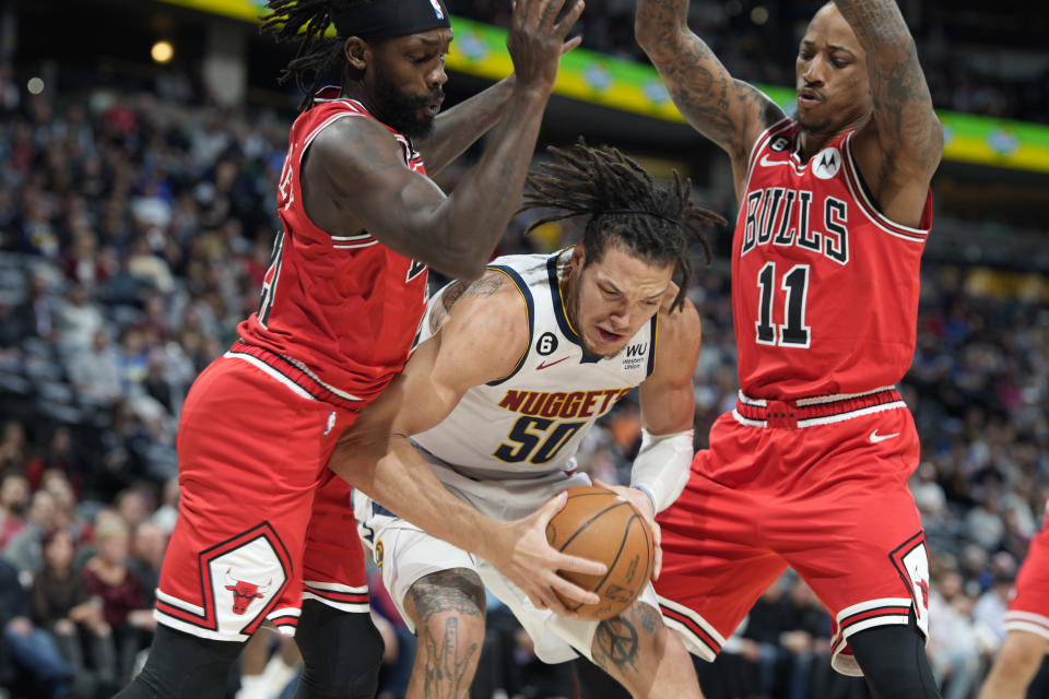 Denver Nuggets forward Aaron Gordon, center, pulls in a loose ball as Chicago Bulls guard Patrick Beverley, left, and forward DeMar DeRozan defend in the first half of an NBA basketball game Wednesday, March 8, 2023, in Denver. (AP Photo/David Zalubowski)