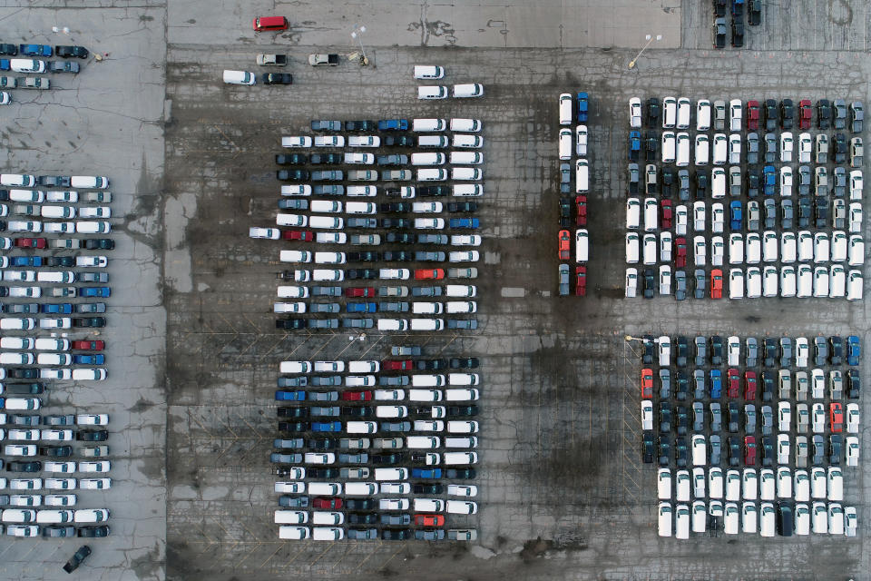 In this aerial photo, mid-sized pickup trucks and full-size vans are seen in a parking lot outside a General Motors assembly plant where they are produced Wednesday, March 24, 2021, in Wentzville, Mo. As the U.S. economy awakens from its pandemic-induced slumber, a vital cog is in short supply: the computer chips that power our cars and other vehicles, and a vast number of other items we take for granted. Ford, GM and Stellantis have started building vehicles without some computers, putting them in storage with plans to retrofit them later.(AP Photo/Jeff Roberson)