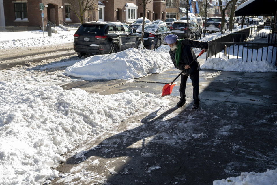 Manjit Bath clears the sidewalk of packed snow in front of India Gate restaurant, after two days of lake-effect snow on Elmwood Avenue in Buffalo, N.Y., Sunday, Nov. 20, 2022. Just south of Buffalo, towns are still working to clear the snowy aftermath of the lake-effect storm, but in parts of the city, normalcy is beginning to return. (Libby March/The Buffalo News via AP)