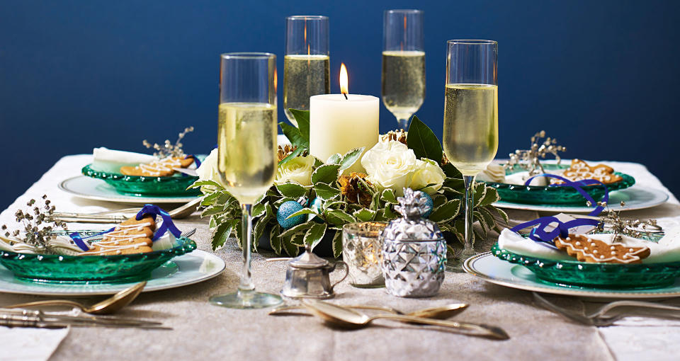 Navy blue dining room with dining table with green plates and wreath and candle Christmas centerpiece idea