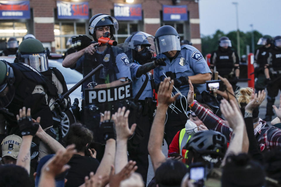 FILE - In this Sunday, May 31, 2020, file photo, a police officer points a hand cannon at protesters who have been detained pending arrest on South Washington Street, in Minneapolis. President Donald Trump has characterized those clashing with law enforcement in the wake of George Floyd’s death under the knee of a Minneapolis police officer as radical-left thugs engaging in domestic terrorism. The Associated Press has found that more than 85 percent of those charged by police were locals. Only a handful appeared to have any affiliation with organized groups involved in the protests. (AP Photo/John Minchillo, File)