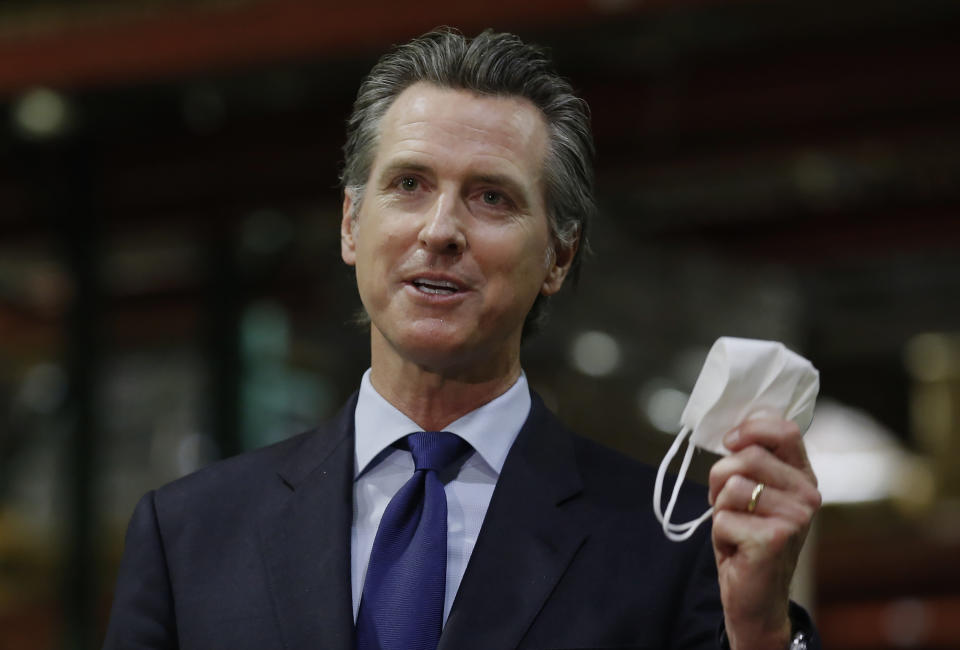 FILE - In this June 26, 2020, file photo, California Gov. Gavin Newsom displays a face mask as he urges people to wear them to fight the spread of the coronavirus during a news conference in Rancho Cordova, Calif. Gov. Newsom announced a new, color-coded process Friday, Aug. 28, 2020, for reopening California businesses amid the coronavirus pandemic that is more gradual than the state's current rules to guard against loosening restrictions too soon. Counties will move through the new, four-tier system based on their number of cases and percentage of positive tests. It will rely on those two metrics to determine a tier: case rates and the percentage of positive tests. (AP Photo/Rich Pedroncelli, Pool, File)