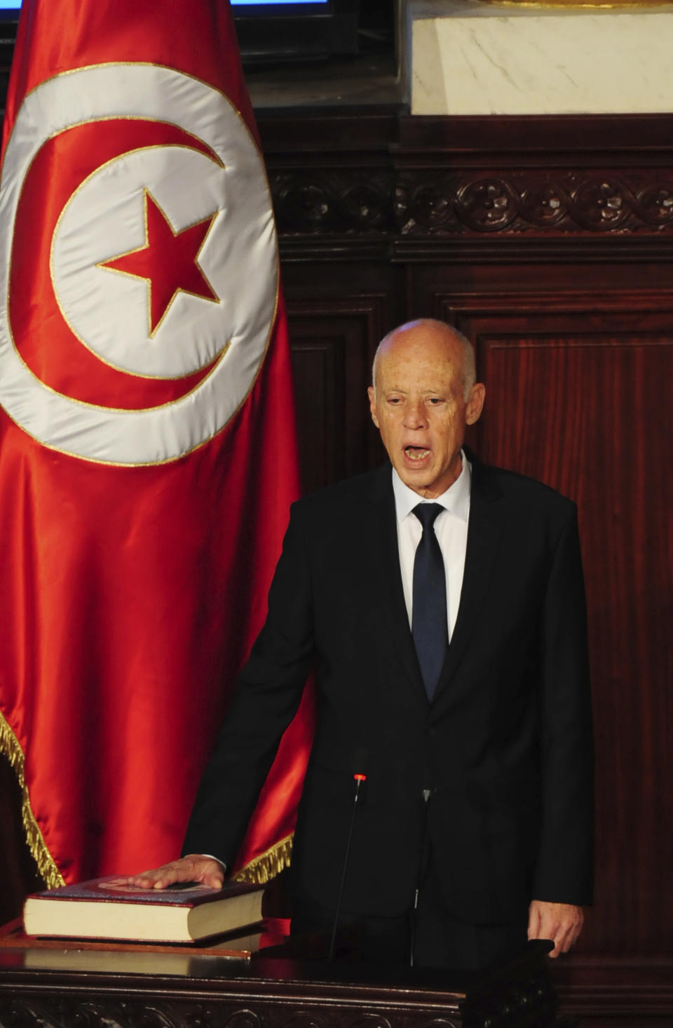 Newly elected Tunisian President Kais Saied puts his hand on the Quran to be sworn in as Tunisian President, in Tunis, Wednesday Oct.23, 2019. Tunisians elected former law professor Kais Saied as president earlier this month to replace President Beji Caid Essebsi, who died in July. (AP Photo/Hassene Dridi)