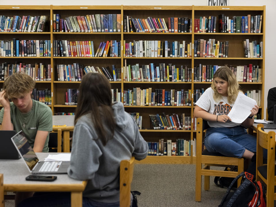 Junior at Robert Lee High School Ammileigh Smith, right, talks with her classmates about an essay she wrote about the pros and cons of school vouchers in Texas, in the school’s library in Robert Lee, Texas on March 9, 2023. (Matthew Busch for NBC News)