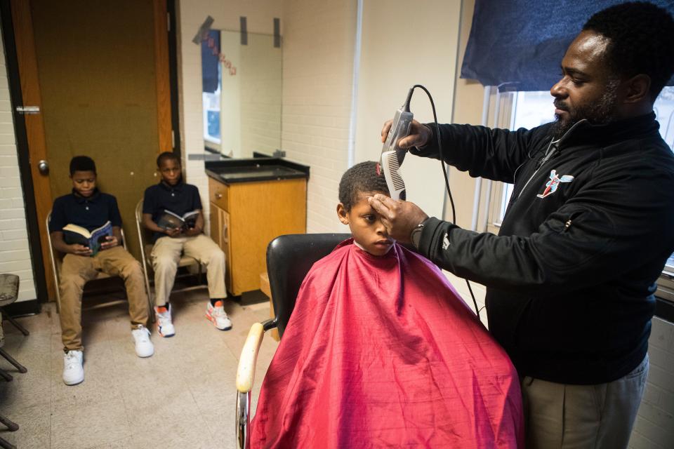 Warner Elementary principal Terrance Newton, right, gives Brandon Ponzo a haircut as he chats with students Jihad Turner, left and Isiah Wright about life and sports at the school Monday, Dec. 16, 2019. The makeshift barbershop gives Newton a chance to bond with his students in a more casual setting and keep his students looking sharp. 