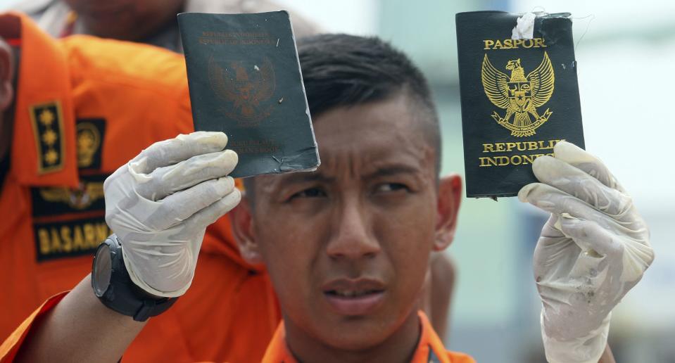 A search and rescue official holds up two passports recovered from the wreckage. Image: AP