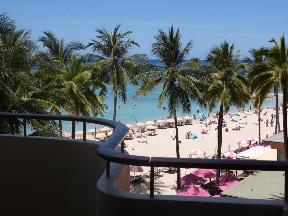 A view of palm trees and water from a balcony at the Royal Hawaiian hotel.