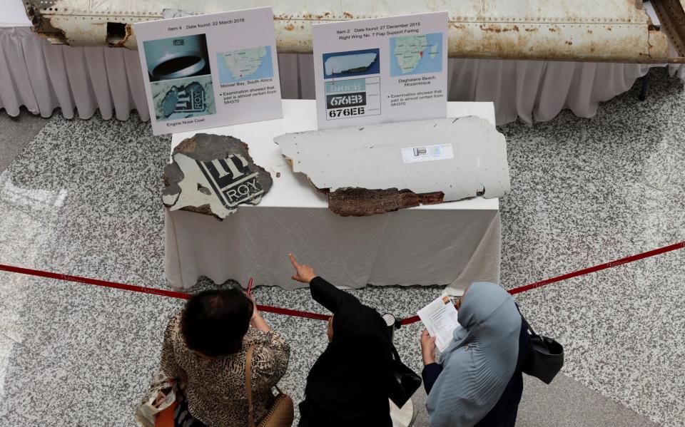 Visitors look at the wreckage of an aircraft believed to be from flight MH370