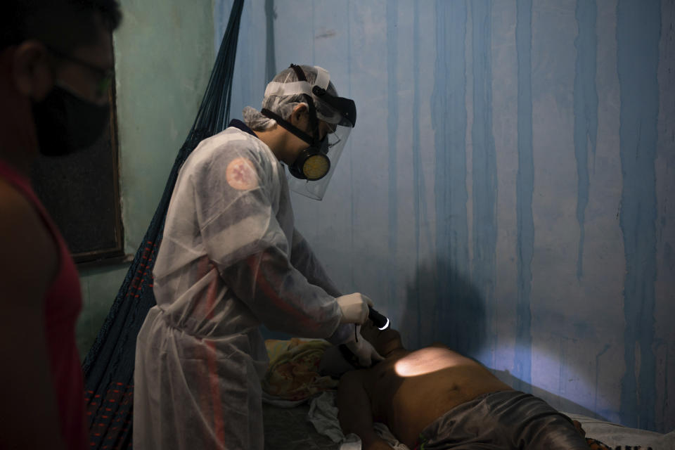 An ambulance doctor checks for the pulse of an elderly man who had just died at his home amid the new coronavirus pandemic in Manaus, Brazil, Thursday, May 21, 2020. Per capita, Manaus is Brazil's major city hardest hit by COVID-19. (AP Photo/Felipe Dana)