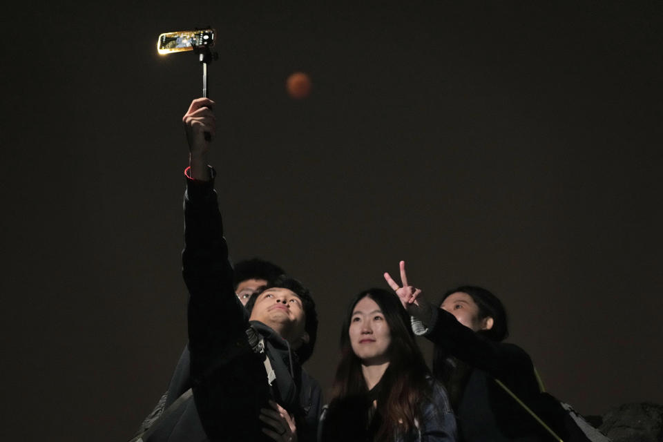 Un grupo de personas se toma un selfie durante el eclipse lunar en Beijing, China, el 8 de noviembre del 2022. . (Foto AP/Ng Han Guan)