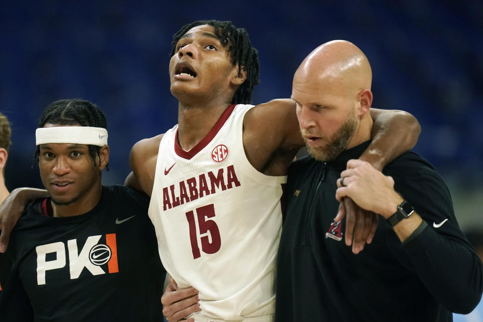 Alabama forward Noah Clowney (15) is helped off the court during the first half of the team's NCAA college basketball game against North Carolina in the Phil Knight Invitational on Sunday, Nov. 27, 2022, in Portland, Ore. (AP Photo/Rick Bowmer)