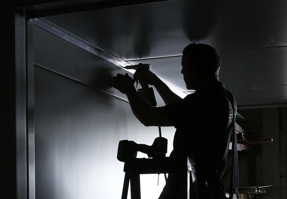 In this photo taken Monday Nov. 11, 2019, employee Brett Petty works on a climate control plant sprouting system for Fodder Works at the Simple Country manufacturing plant in Grass Valley, Calif. Power outages, implemented by Pacific Gas & Electric in hopes of preventing wildfires have been unpredictable and making it hard for companies to operate. Because power could be turned off or on at any time, Kyle Chittock, who runs Simple Country, couldn't know in advance whether to tell staffers to come in or start home. (AP Photo/Rich Pedroncelli)