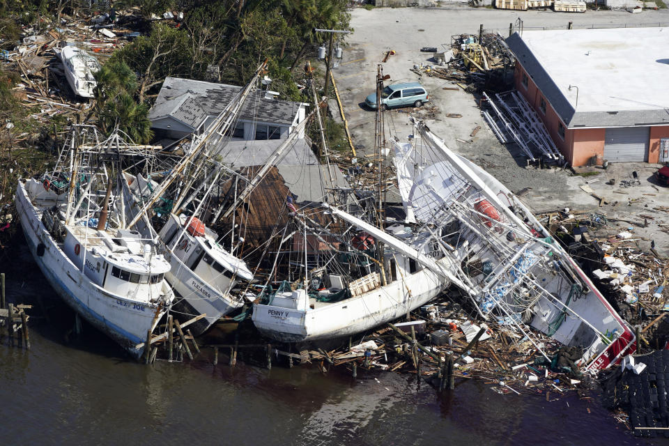 In this aerial photo, damaged boats and debris are stacked along the shore in the aftermath of Hurricane Ian, Thursday, Sept. 29, 2022, in Fort Myers, Fla. (AP Photo/Wilfredo Lee)