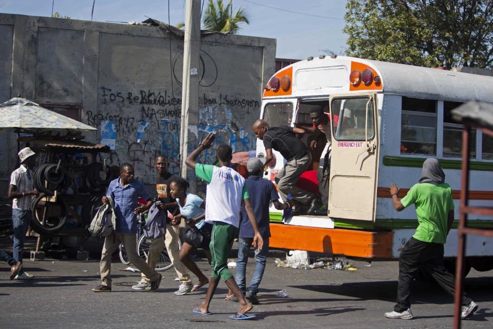 Protesters make commuters exit their bus so they can block the road with the vehicle as they protest final election results in Port-au-Prince, Haiti, Tuesday, Jan. 3, 2017. An electoral tribunal certified the presidential election victory of first-time candidate Jovenel Moise. (AP Photo/Dieu Nalio Chery)