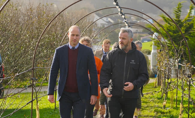 william walks through an orchard with a man followed by people