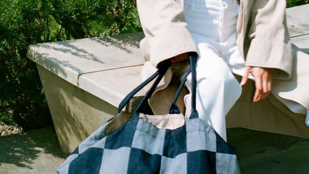 a woman wearing a white coat and a skirt with a checkered bag