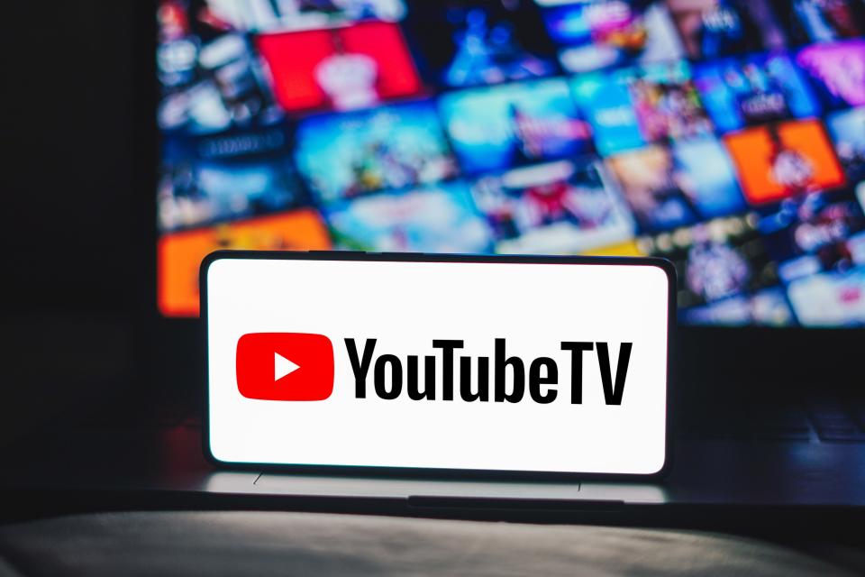 YouTube TV logo on a mobile phone with TV screens in the background.