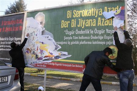 Plainclothes police officers tear down a billboard with a picture of imprisoned Kurdish rebel leader Abdullah Ocalan in Diyarbakir February 11, 2014. REUTERS/Stringer