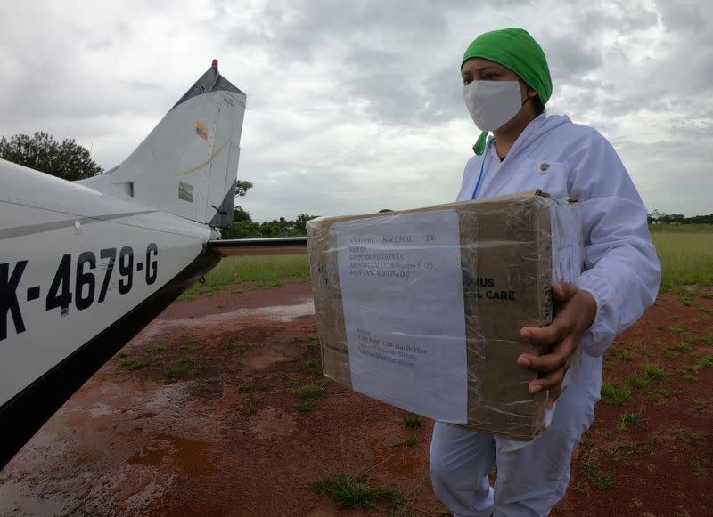 Bacteriologist Diana Carolina Galvan from the Hospital de La Primavera using protection elements carries a box with samples of the coronavirus disease (COVID-19) that will be processed in Bogota, in La Primavera