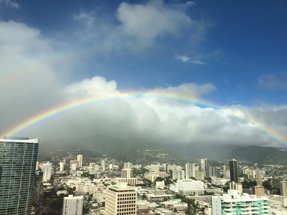 Rainbow arching over a cityscape with clouds in the background