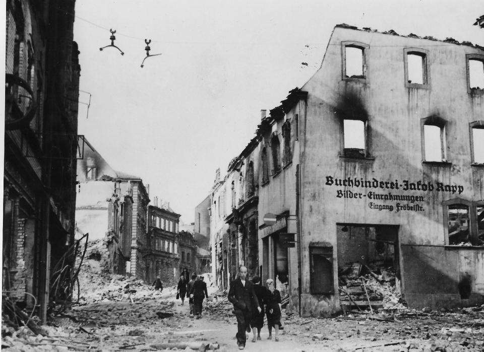Dazed citizens walk through debris-littered streets in the German town of Pirmasens following Allied shelling April 7, 1945.