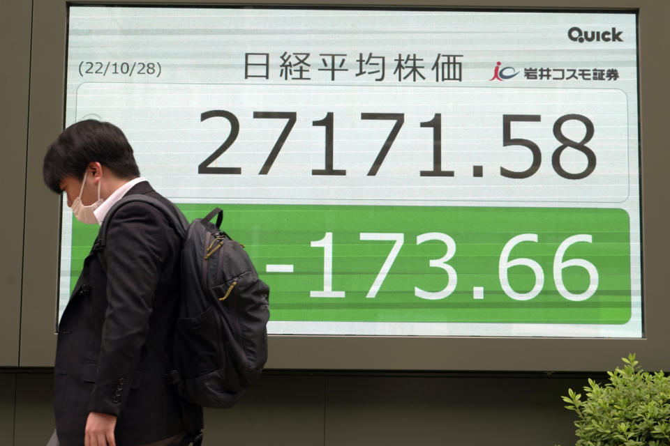 A person walks in front of an electronic stock board showing Japan's Nikkei 225 index at a securities firm Friday, Oct. 28, 2022, in Tokyo. Shares were mostly lower in Asia on Friday after a mixed session on Wall Street, where tech sector losses offset gains in other parts of the market. (AP Photo/Eugene Hoshiko)