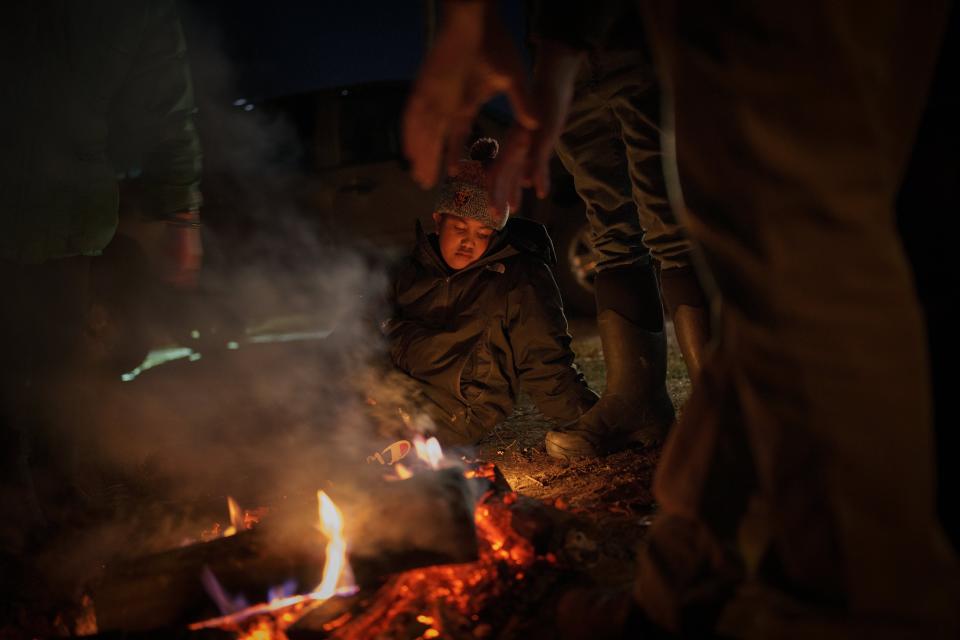 Jaylon Rising Sun Givens, 8, warms up by a fire after fishing on Pokegama Lake during a youth spearfishing event Sunday, April 21, 2024, in Lac Du Flambeau, Wis. Givens caught 4 walleye during the event. (AP Photo/John Locher)