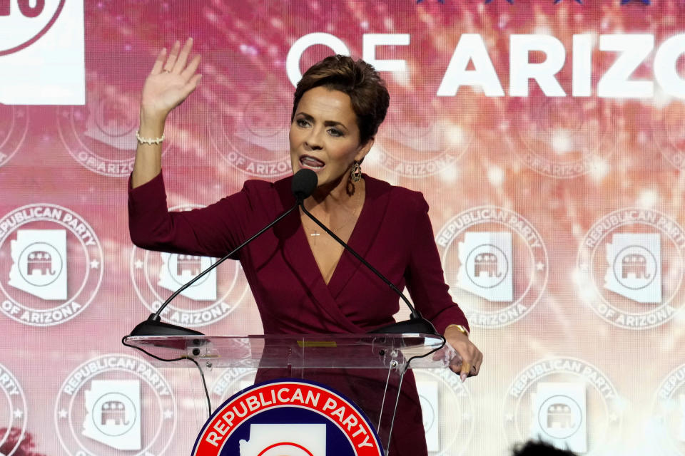 Kari Lake at the microphone in front of a backdrop with seals saying: Republican Party of Arizona.