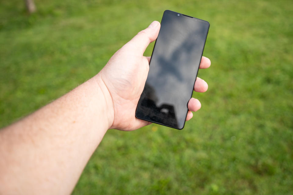 A black Sony Xperia 1 V camera phone being held in a left hand