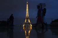 <p>People with umbrellas walk at the Palais de Chaillot near the illuminated Eiffel Tower in Paris on July 13, 2017, as President Donald Trump and French President Emmanuel Macron attend a dinner with their wives at the restaurant ‘Le Jules Verne’ on the tower’s second floor. (Photo: Jean-Sebastien Evrard/AFP/Getty Images) </p>