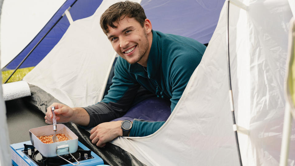 Young man in his tent having beans for breakfast in The Lake District in Cumbria