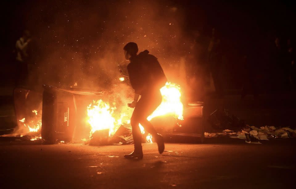 A woman ran past burning garbage during a demonstration in Oakland, California. Photo: Reuters