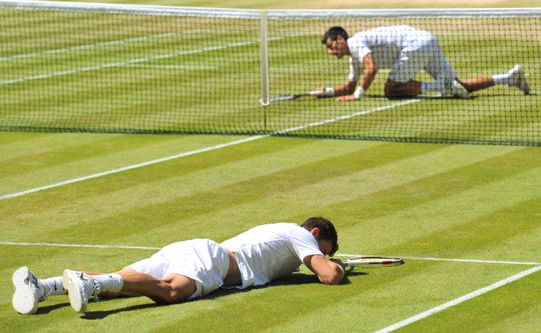 Bulgaria's Grigor Dimitrov (front) and Serbia's Novak Djokovic (back) slip and fall down during their men's singles semi-final match during the 2014 Wimbledon Championships in London, on July 4, 2014