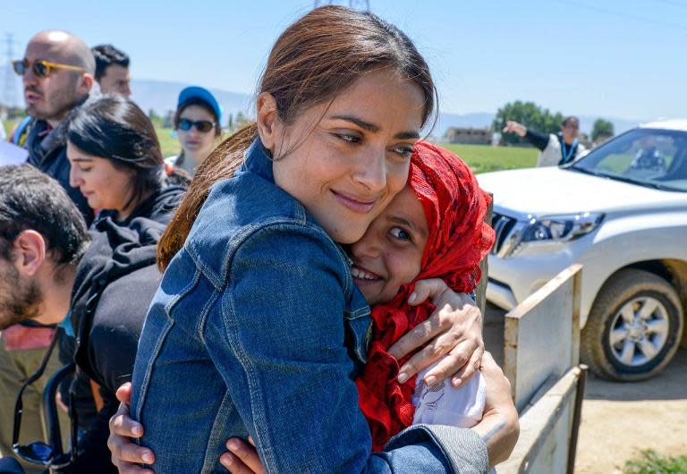 Handout picture released by UNICEF and taken on April 25, 2015, shows Mexican-US actress Salma Hayek (L) giving a hug to a young Syrian refugee at a camp in Lebanon's eastern Bekaa Valley as she campaigns with UNICEF to raise funds for refugees