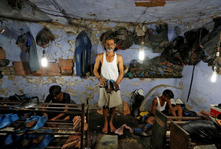A shoemaker poses for a picture in an underground workshop in Agra, India, June 9, 2017. REUTERS/Cathal McNaughton/Files