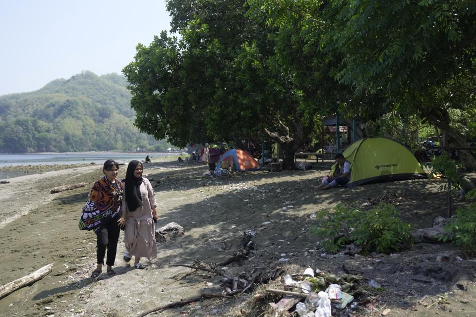 Tourists walk on a beach where maleos are known to lay their eggs, in Mamuju, West Sulawesi, Indonesia, Sunday, Oct. 29, 2023. With their habitat dwindling and nesting grounds facing encroachment from human activities, maleo populations have declined by more than 80% since 1980, an expert said.(AP Photo/Dita Alangkara)