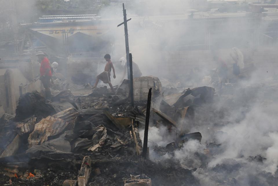 In this Tuesday, Jan. 10, 2017 photo, residents of a community in suburban Navotas sift through the smoldering debris following an early morning fire, in northern suburb of Manila, Philippines. Fire officials said the fire razed more than 600 shanty homes leaving more than 1,500 families homeless. (AP Photo/Bullit Marquez, File)