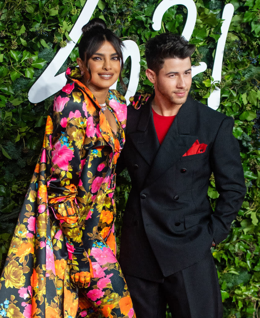 Priyanka, in a colorful outfit, and Nick smiling and standing together