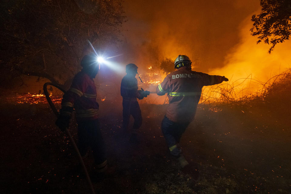 Fighters try to extinguish a wildfire near Cardigos village, in central Portugal on Sunday, July 21, 2019. About 1,800 firefighters were struggling to contain wildfires in central Portugal that have already injured people, including several firefighters, authorities said Sunday. (AP Photo/Sergio Azenha)