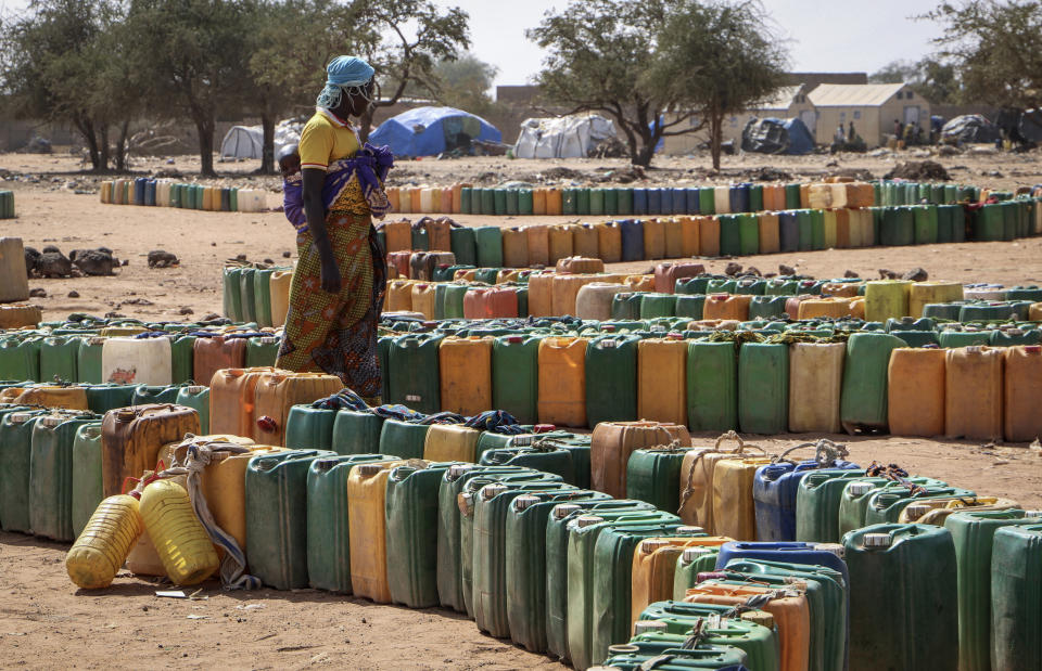 In this photo taken Monday, Dec. 9, 2019, plastic containers belonging to displaced people sit queued up in lines, waiting their turn to be filled with water from a well, at a makeshift camp for the internally displaced in Barsalogho, in northern Burkina Faso. The rapid spread of the coronavirus has raised fears about the world’s refugees and internally displaced people, many of whom live in war-ravaged countries that are ill-equipped to test for the virus or contain a possible outbreak. (AP Photo/Sam Mednick)