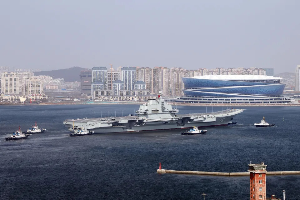 Aircraft carrier Liaoning sets out for sea trials at Dalian shipyard with the help of towboats.