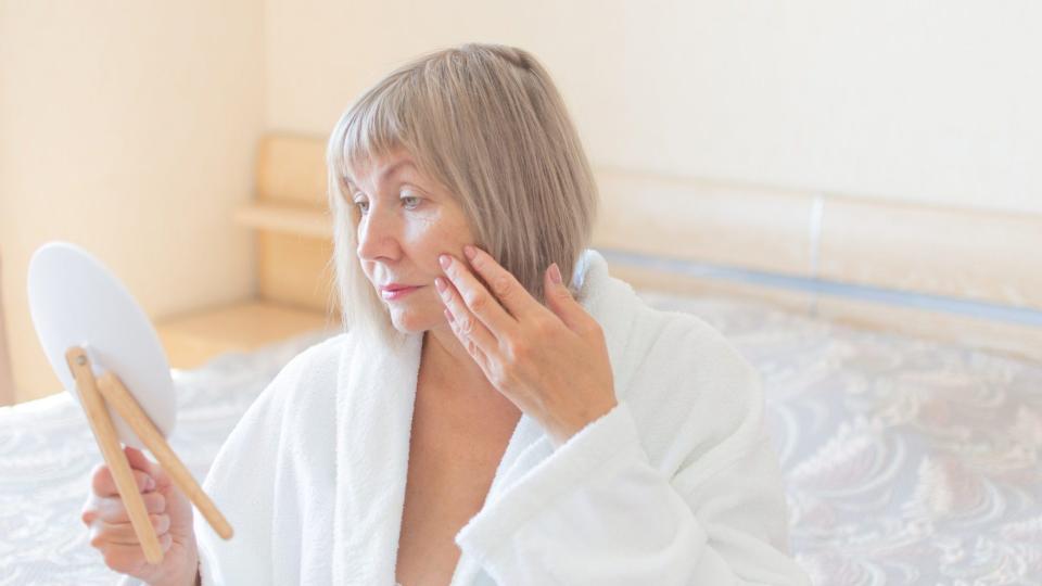 Mature woman looking at skin in mirror