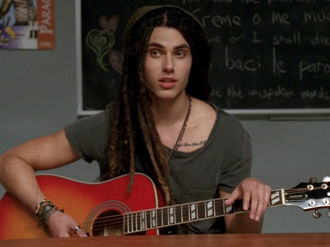 Samuel Larsen on "Glee" wearing a green shirt and playing a guitar