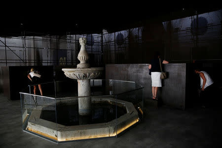 People look at dioramas contained inside iron boxes as part of the "S.A.C.R.E.D" installation by Chinese artist Ai Weiwei during a media preview at the cathedral in Cuenca, Spain, July 21, 2016. Picture taken July 21, 2016. REUTERS/Susana Vera