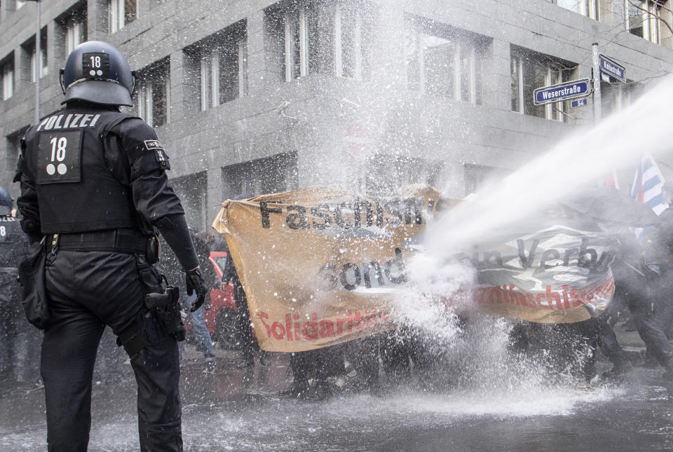 The police use a water cannon on the opponents of the "lateral thinking" demonstration in the city centre under the motto "No lockdown for Bembeltown! " in Frankfurt, Germany, Saturday, Nov.14, 2020. (Boris Roessler/dpa via AP)