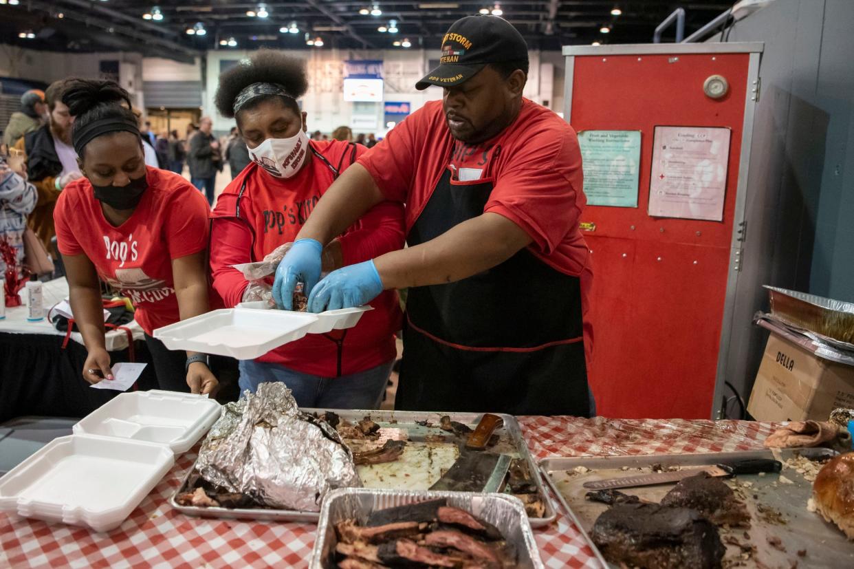 In this Feb. 5, 2022 photo, John Capers, owner of Pops Family Kitchen, prepares orders during Que the Creek BBQ Festival at Kellogg Arena in Battle Creek, Mich. Capers recently graduated from Northern Initiatives Fast Track small business 10-week program, aimed at helping entrepreneurs grow and manage their business startups.